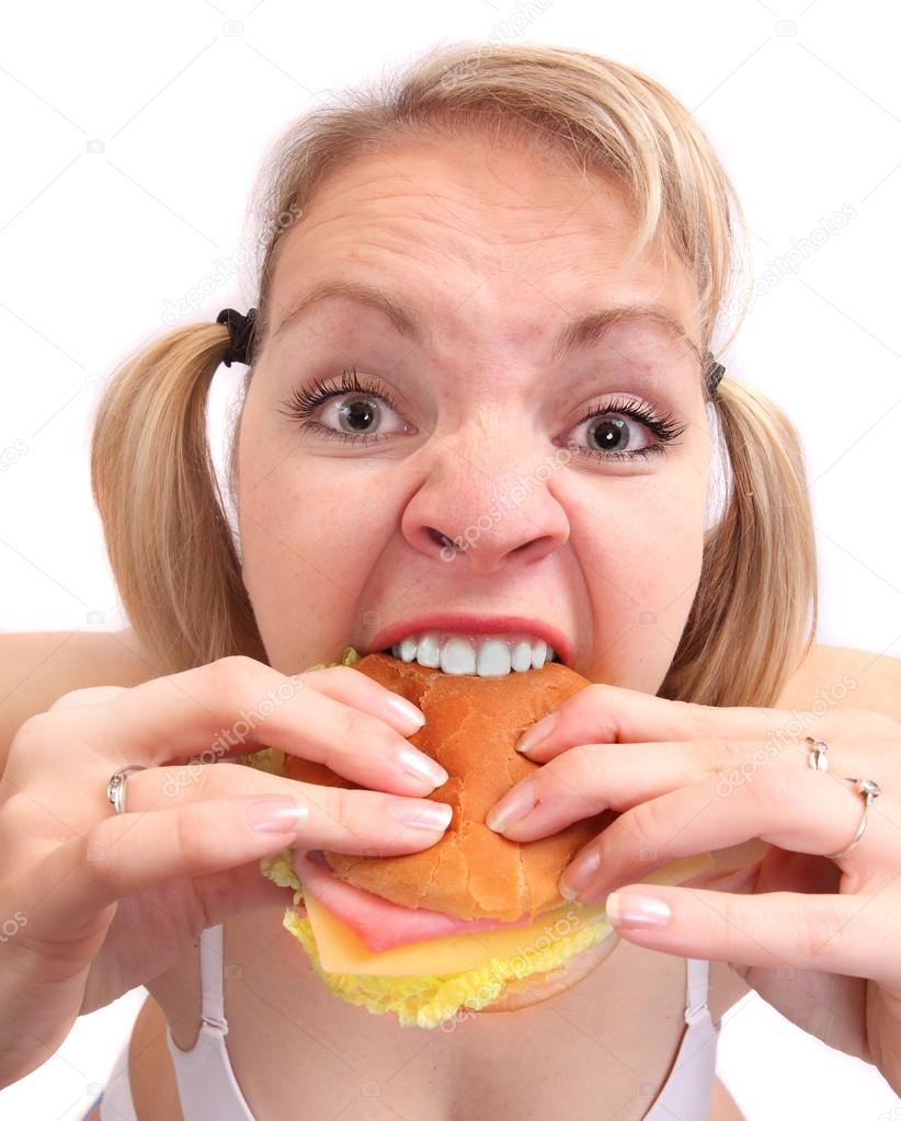 Funny picture of a hungry and angry overweight woman eating tasty sandwich.