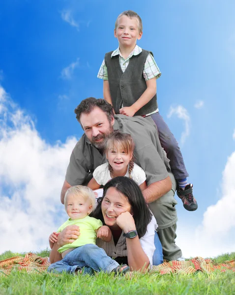 Bonne famille ensemble sur l'herbe contre le ciel bleu . — Photo