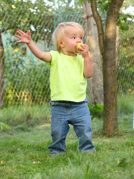 Chica agricultora en el huerto comiendo manzana fresca madura . — Foto de Stock