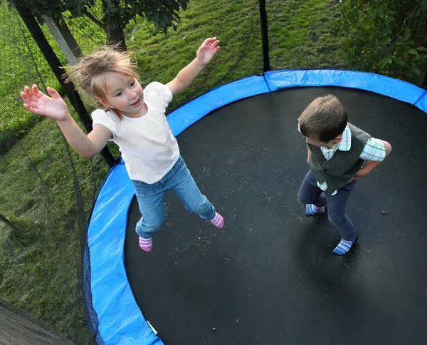 Dwoje dzieci śmieszne, skoki na trampolinie odkryty. — Zdjęcie stockowe