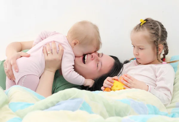幸せな家族。若い母親はベッドに彼女の子供たちと遊ぶ. — ストック写真
