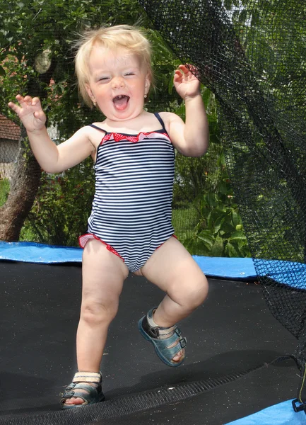 Chica feliz jugando en un trampolín de jardín . — Foto de Stock