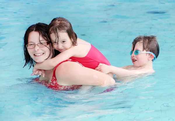 Familia feliz nadando en una piscina . Imagen De Stock