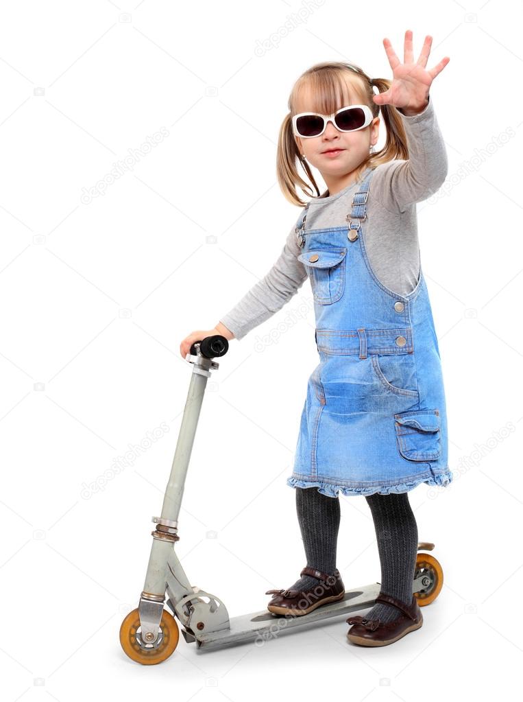 Little girl riding her children scooter.