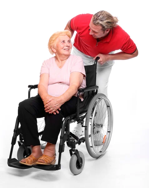 Idosa paraplégica sentada em uma cadeira de rodas e seu enfermeiro — Fotografia de Stock