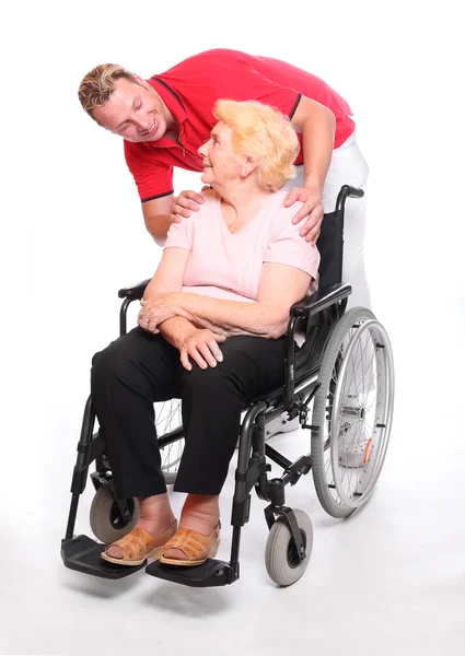 Idosa paraplégica sentada em uma cadeira de rodas e seu enfermeiro — Fotografia de Stock