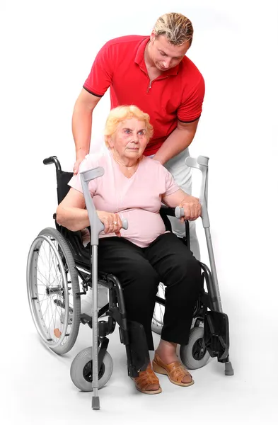 Paraplegic woman sitting in a wheelchair and her male nurse. — Stock Photo, Image