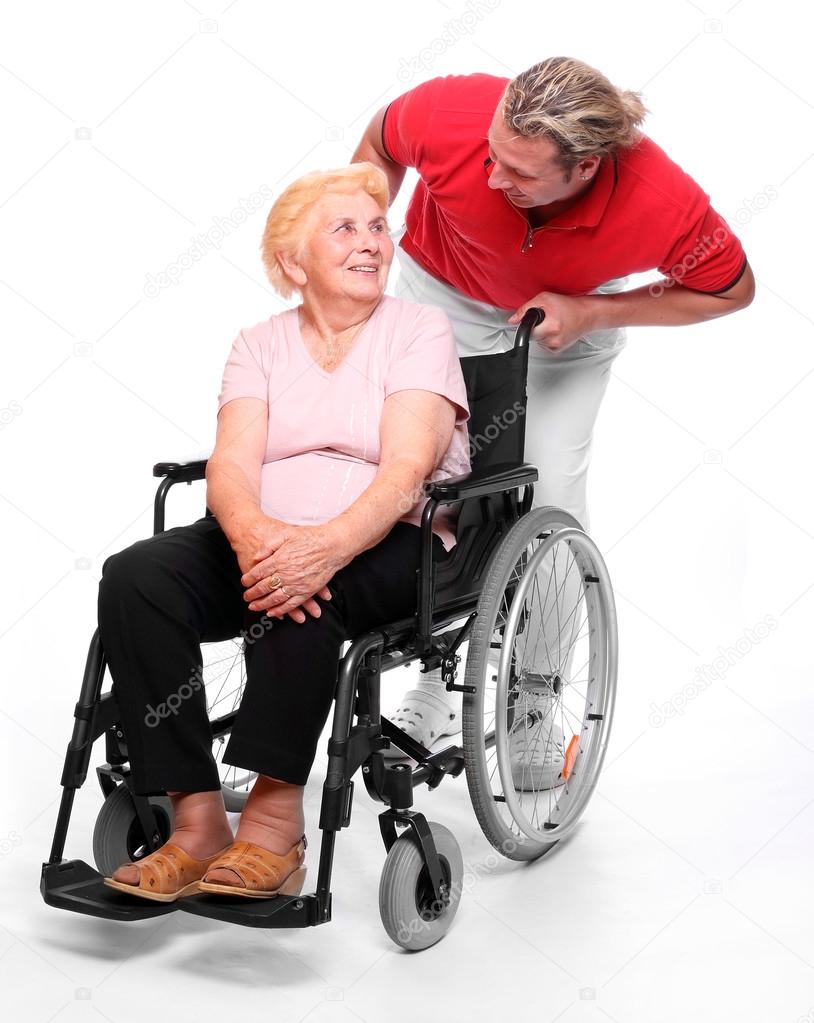 Elderly paraplegic woman sitting in a wheelchair and her male nurse