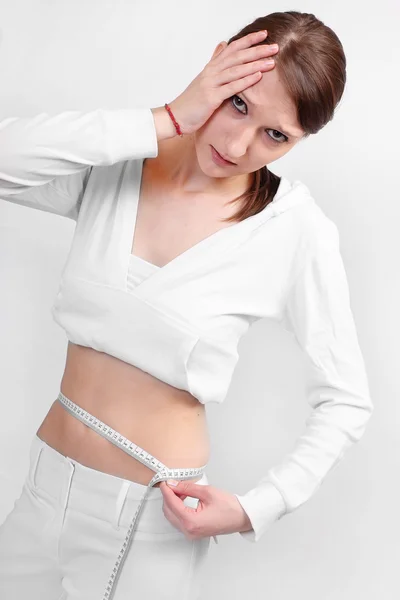 Nahaufnahme einer jungen Frau misst ihren Taillenbauch per Meterstab. — Stockfoto