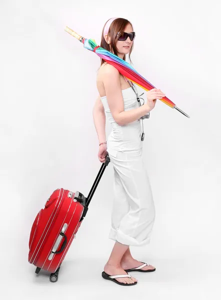 Mujer joven feliz va de vacaciones con su maleta y paraguas de arco iris . —  Fotos de Stock