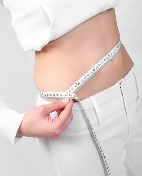 Close up of young woman measure her waist belly by metre-stick. — Stock Photo, Image