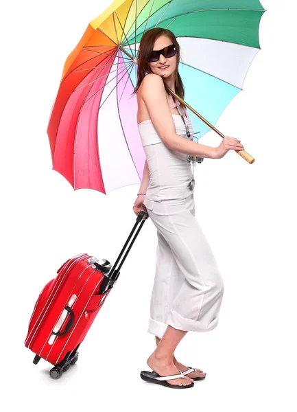 Mujer joven feliz va de vacaciones con su maleta y paraguas de arco iris . — Foto de Stock