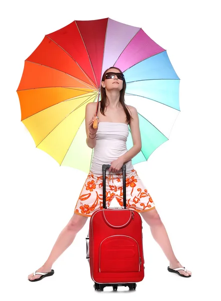 Счастливая молодая женщина собирается в отпуск со своим чемоданом и радужным зонтиком . — стоковое фото
