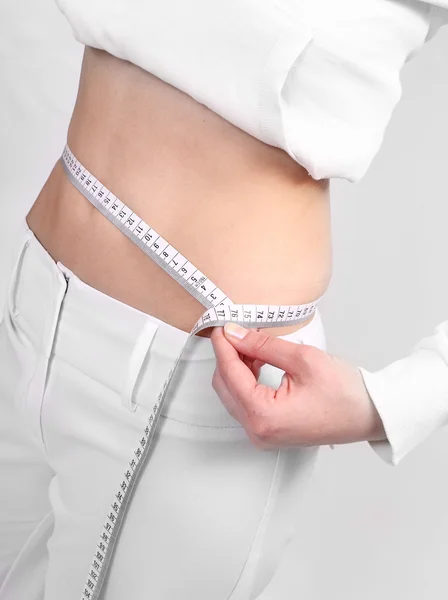 Primer plano de mujer joven medir su cintura vientre por metro-palo . — Foto de Stock
