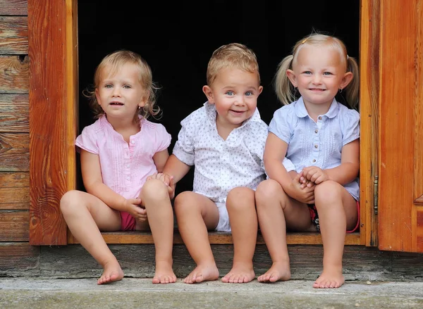 Niños divertidos jugando en la puerta de una casa rural . — Foto de Stock