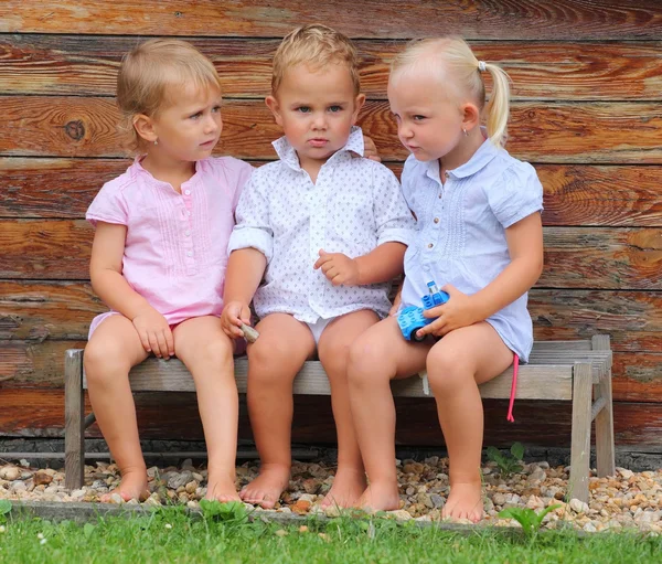 Drôle de frères et sœurs sur un banc rural . — Photo