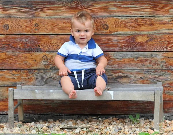Niño sentado en el banco rural . — Foto de Stock
