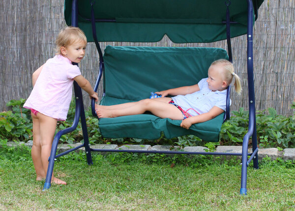 Funny kids playing on a garden swing.
