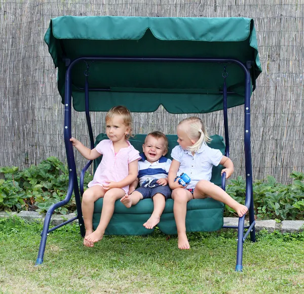 Funny kids playing on a garden swing. — Stock Photo, Image