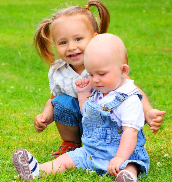 Два счастливых играющих ребенка на зеленой траве — стоковое фото