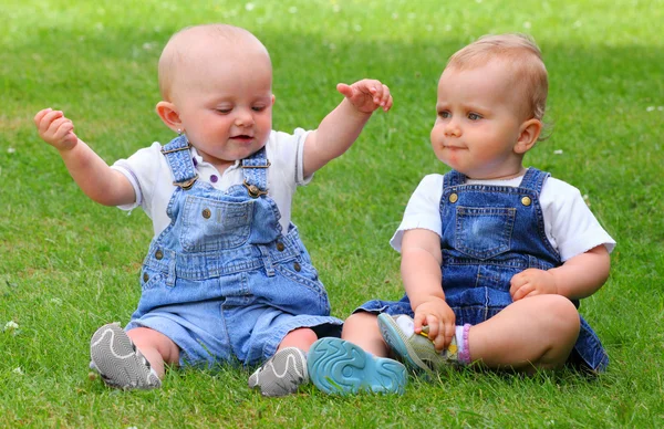 緑の牧草地に 2 人の話している子供. — ストック写真