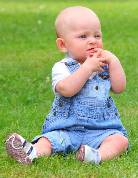 Pequeño niño sentado en una hierba . — Foto de Stock