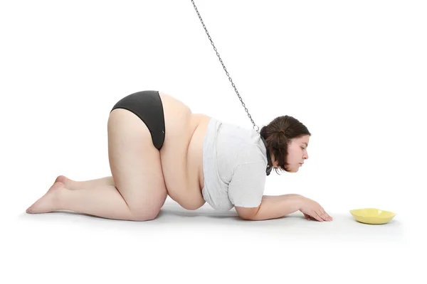 Grappig beeld van een hongerige zwaarlijvige vrouw geketend in de buurt van plaat met voedsel. dieet concept. — Stockfoto