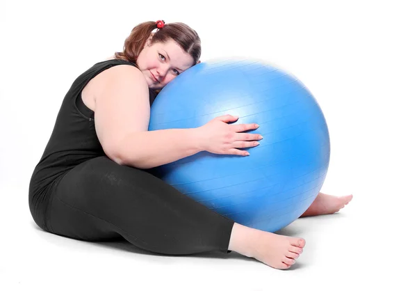 Aufnahme einer glücklichen übergewichtigen jungen Frau mit blauem Ball auf weißem Hintergrund. — Stockfoto