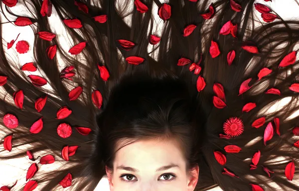 Beautiful woman laying in the white studio background with flowers in her hair. — Stock Photo, Image