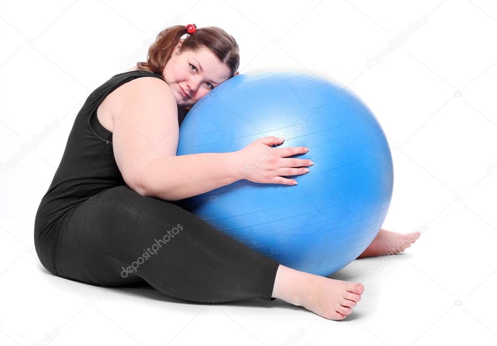 Shot of a happy overweight young woman with blue ball on a white background.