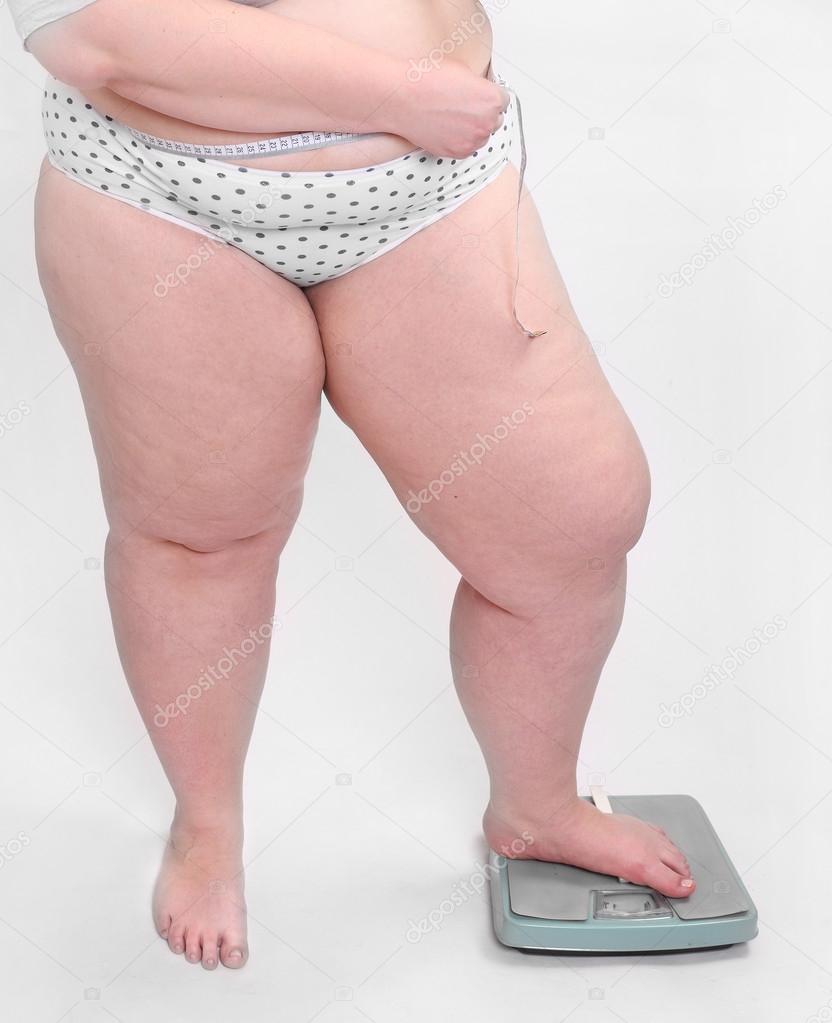 Happy overweight woman measure her waist belly by metre-stick on a weighing machine.