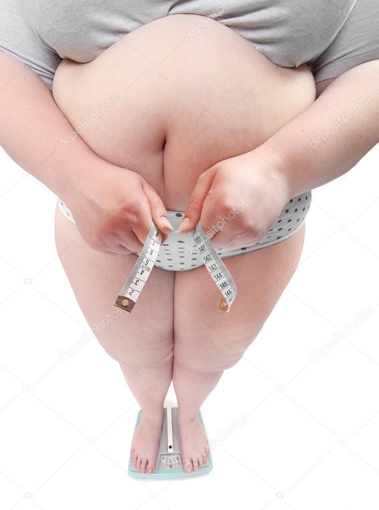 Happy overweight woman with big breast measure her waist belly by metre-stick.