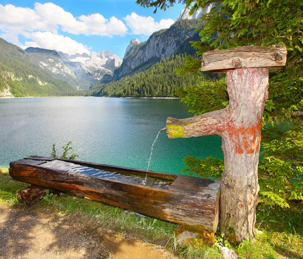 Fountain with drinking water over mountain lake — Stock Photo, Image