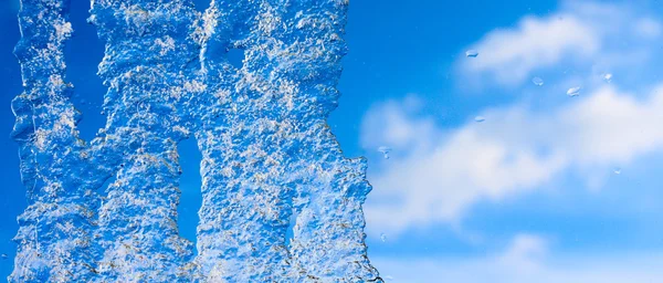 Nahaufnahme einer Eiszapfe gegen den sonnigen Himmel. — Stockfoto