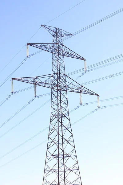 Turnul de înaltă tensiune și liniile electrice împotriva cerului albastru . — Fotografie, imagine de stoc