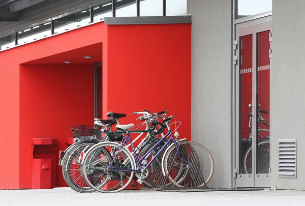 Several old bicycles at door to modern building