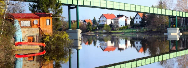 Houses on bank and iron bridge — Stock Photo, Image