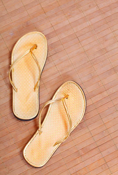 Pair of golden flip flops on the bamboo mat. — Stock Photo, Image