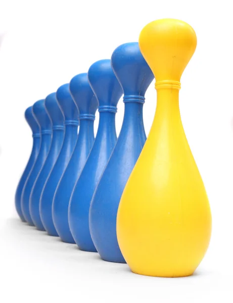 Spilla da bowling gialla tra spilli blu comuni — Foto Stock