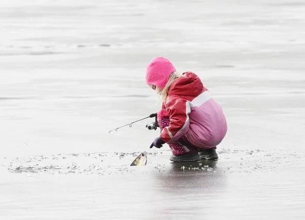 Malé dítě rybaří na zamrzlém jezeře v zimě. — Stock fotografie
