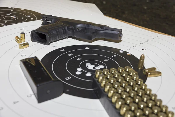 Pistola y municiones sobre la puntuación de diana — Foto de Stock
