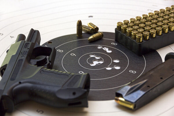 Gun and ammunition over bullseye score