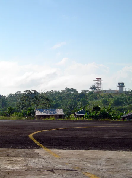 Luchthaven asfalt baan met huizen in de jungle — Stockfoto