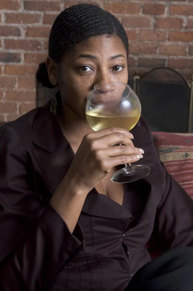 Mulher sorridente no sofá com copo de vinho — Fotografia de Stock