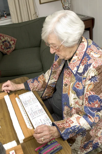 Senior woman at the game table — Stock Photo, Image