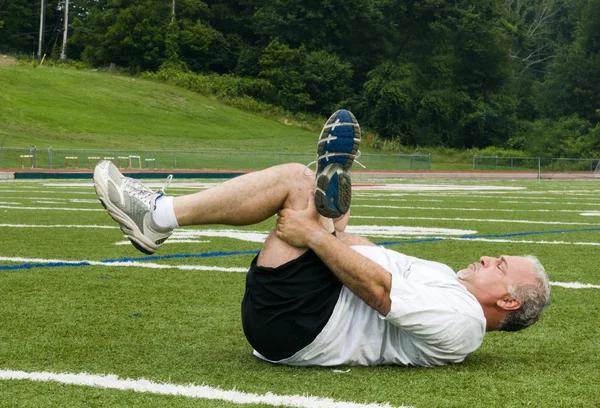 Uomo di mezza età che si allunga ed esercita sul campo sportivo — Foto Stock