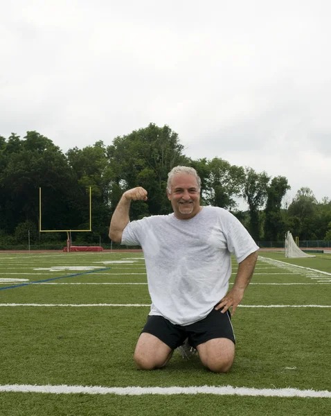 Hombre de mediana edad estiramiento y ejercicio en el campo de deportes — Foto de Stock