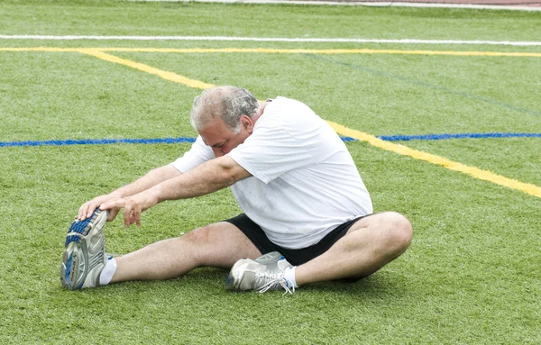 Homem de meia idade alongamento e exercício no campo de esportes — Fotografia de Stock