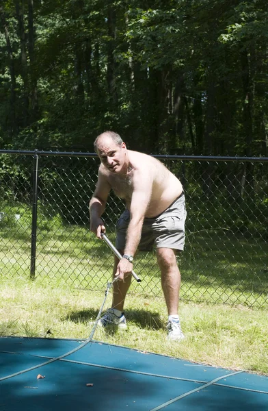 Homeowner removing swimming pool cover at suburban house — Stock Photo, Image