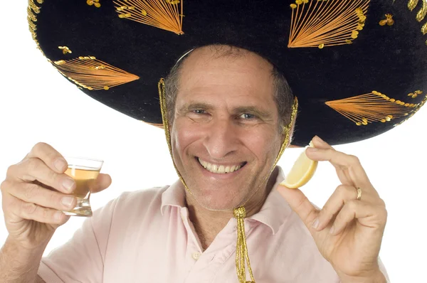 Mann mittleren Alters trägt mexikanischen Sombrero-Hut und trinkt Tequila — Stockfoto